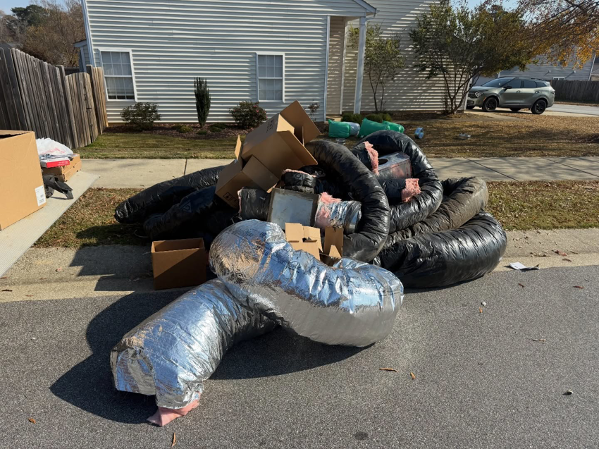 A large pile of old HVAC ductwork and cardboard boxes on a driveway for removal by Junkslingers NC in Cary, NC.