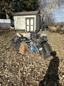 A large pile of household junk and debris in a backyard, ready for removal by Denver Dumpsters in Denver, CO.