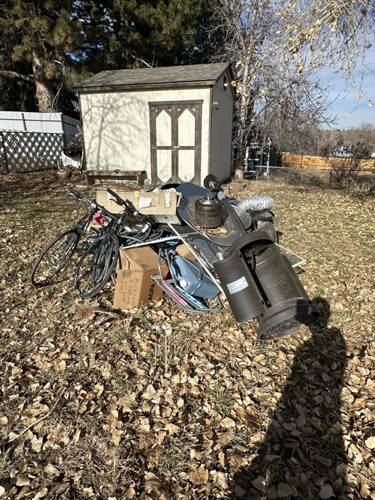 A large pile of household junk and debris in a backyard, ready for removal by Denver Dumpsters in Denver, CO.