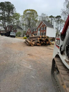 A large pile of logs and a skid steer, indicating recent tree removal by Elegant Tree Service in Atlanta, GA.