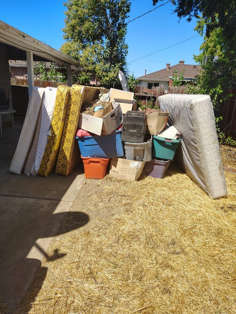A large pile of mattresses, boxes, and bins in a backyard, ready for junk removal by Sac Junk in Rancho Cordova, CA