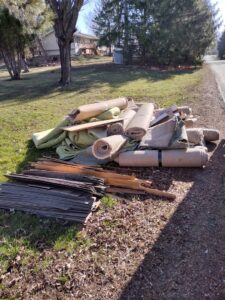 A large pile of old rolled-up carpet and wood planks ready for removal by One Call Junk Removal in Minneapolis, MN