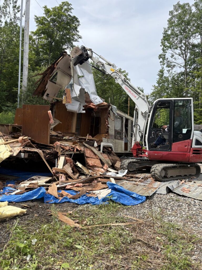 A large pile of old furniture and construction debris outside a building, ready for junk removal by Tiny's Trash & Hauling Service L.L.C in Williamstown, VT