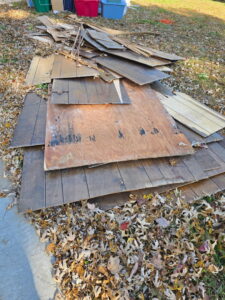 A pile of old siding and wood panels on the ground ready for removal by Waste Walkers Dispatch in Springfield, MO.