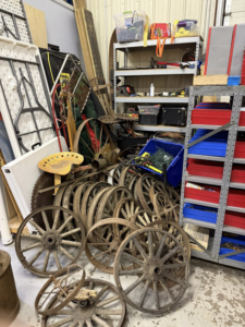 A large pile of old wooden wagon wheels and metal parts awaiting junk removal by Kersten Family Junk Removal in Eau Claire, WI.