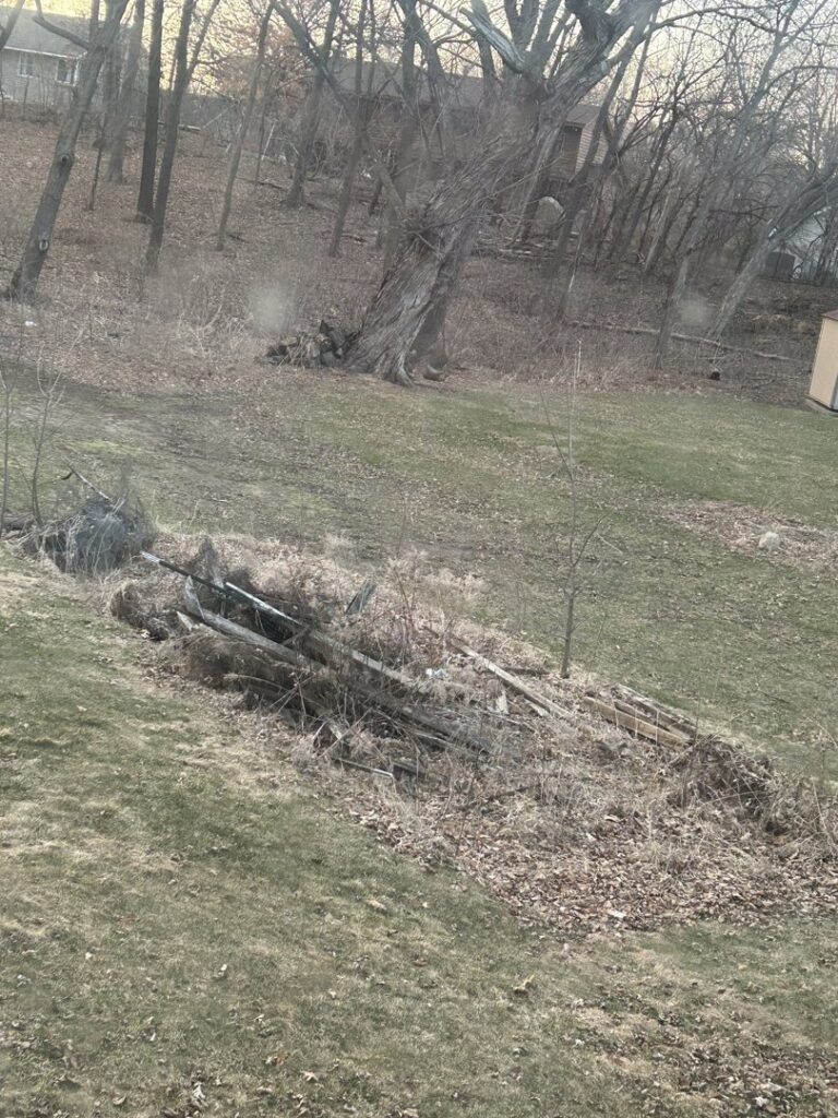 A pile of old wood and various debris in a grassy area ready for removal by One Call Junk Removal in Minneapolis, MN
