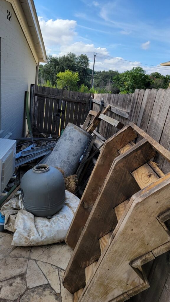 A pile of outdoor junk, including wooden pallets and a metal barrel, ready for removal by Silverhull Junk Removal in San Antonio, TX
