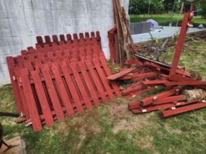 A pile of red fence panels and other wooden debris ready for removal by Quick Lift Junk Removal in Hagerstown, MD.
