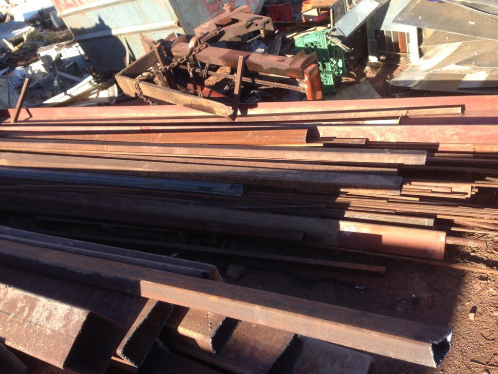 A large pile of rusty metal beams and bars at a scrap yard operated by RZR Recycling in Phoenix, AZ.