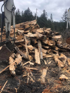 A large pile of split wood and debris from tree removal services by Jere's Tree Service in Kodiak, AK.