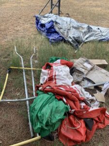 A pile of tarps, metal poles, and cardboard boxes on grass, ready for removal by Roadrunner JunkSmart Solutions LLC in Las Cruces, NM.