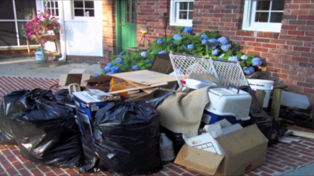 A large pile of trash bags, boxes, and miscellaneous junk items outside a brick house for A1 Junk Removal Of Tucson, AZ.
