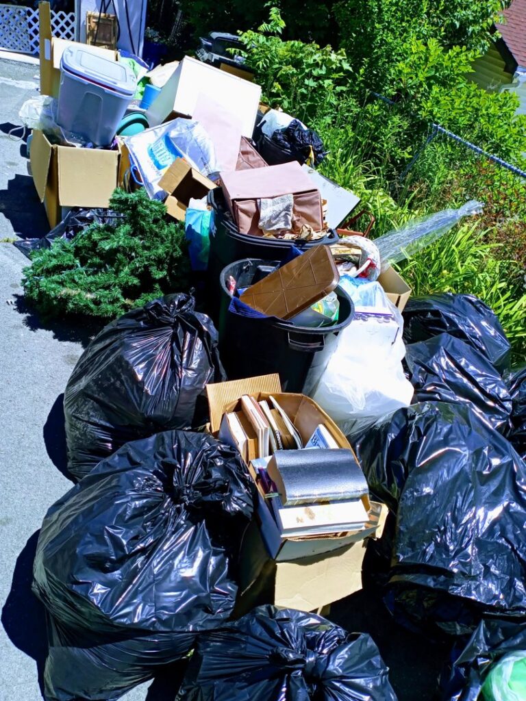 A large pile of black trash bags, cardboard boxes, and various junk items awaiting removal by Junken Monkeys Hauling Company in Scranton, PA.