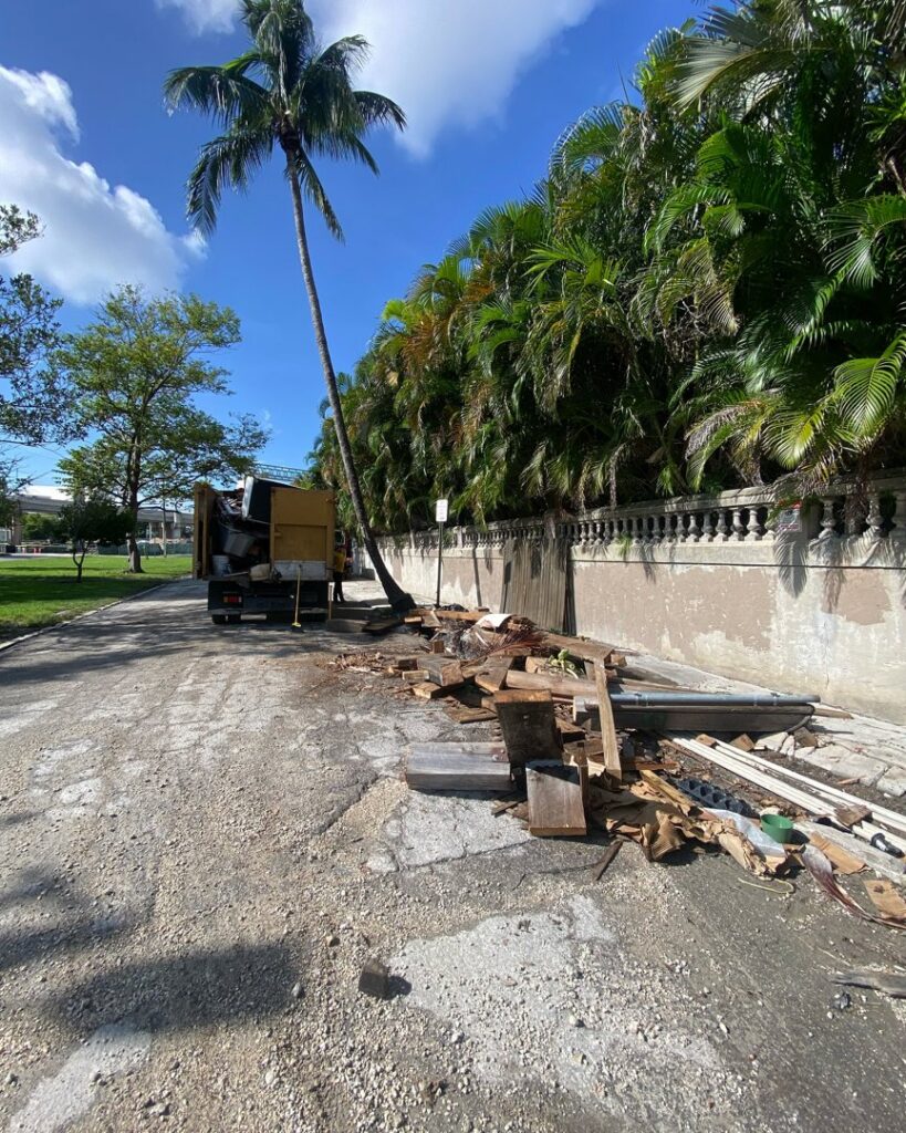 A large pile of wood and construction debris on the roadside, awaiting removal by Junk Be Gone in Miami, FL.