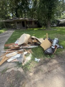 A large pile of wood, cardboard, and trash bags on a lawn, ready for junk removal by LP Junk Removal in Birmingham, AL.