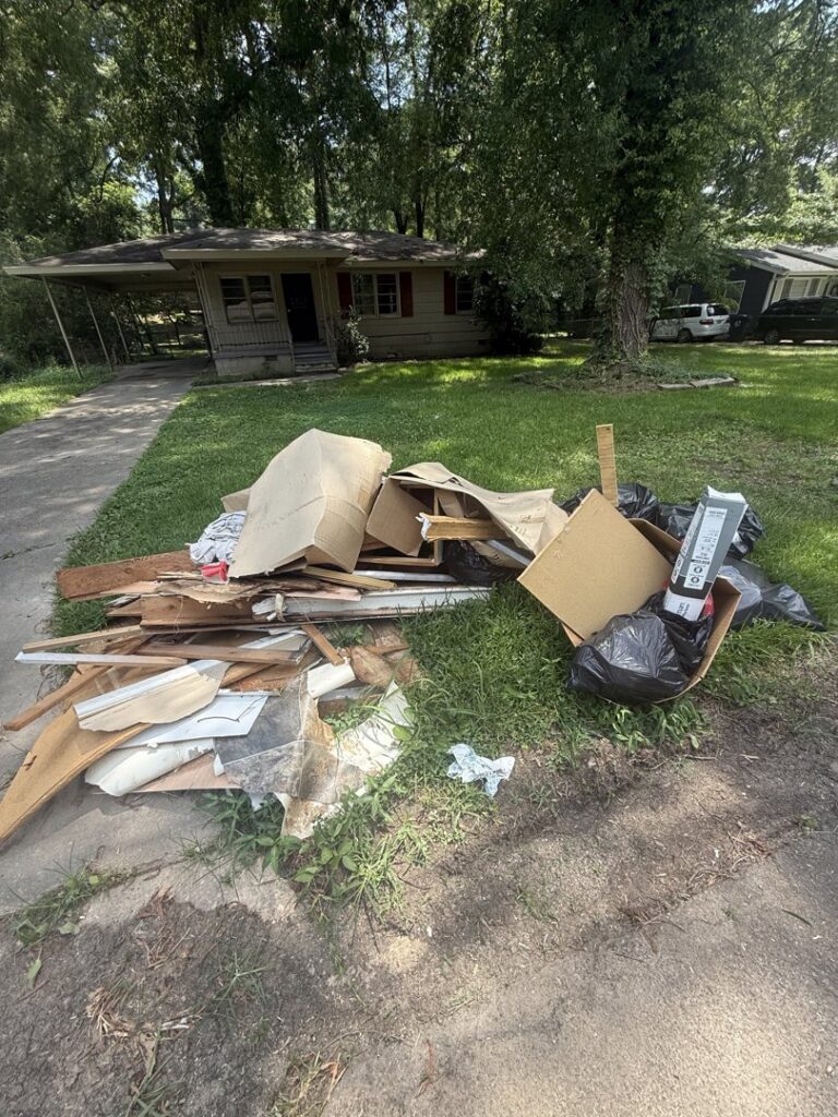 A large pile of wood, cardboard, and trash bags on a lawn, ready for junk removal by LP Junk Removal in Birmingham, AL.