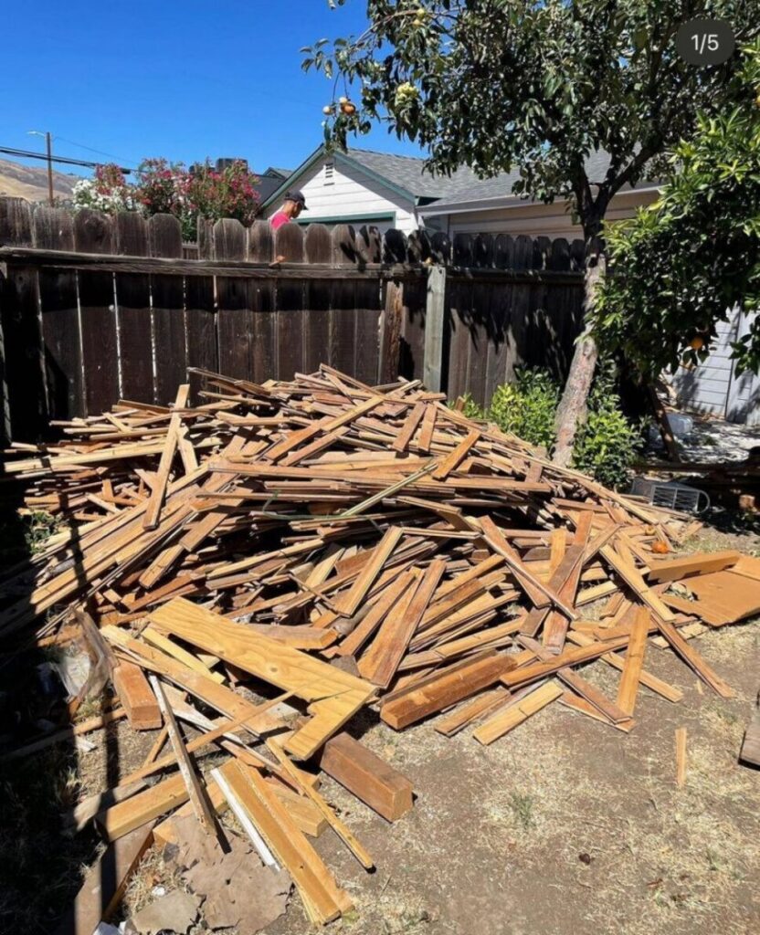 A large pile of wooden planks and construction debris in a backyard, ready for removal by Stars Junk Removal in San Jose, CA.
