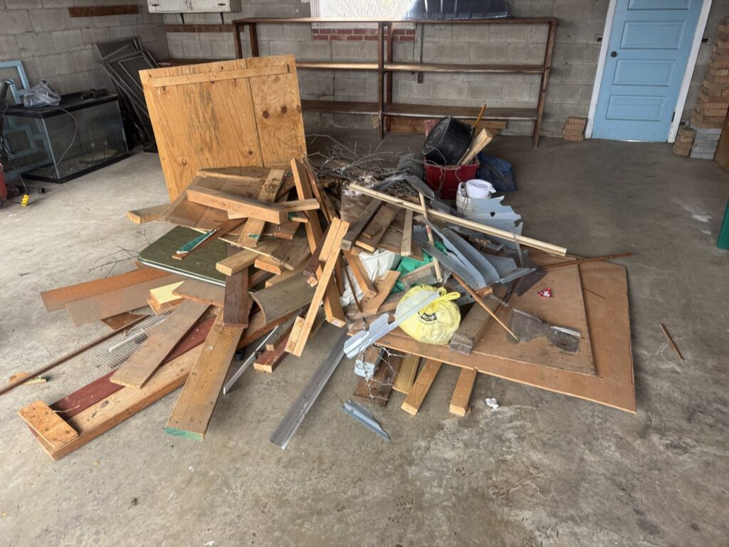 A pile of wood scraps, metal, and various debris in a garage ready for removal by Quick Lift Junk Removal in Hagerstown, MD.