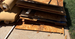 A pile of wood scraps, plywood, and rolled-up carpet ready for removal by KC Family Haul in Kansas City, KS.