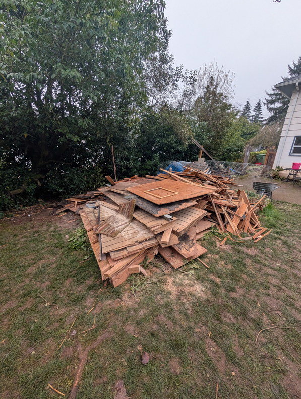 A large pile of wooden debris and old fencing in a backyard, ready for removal by Patriot Hauling & Junk Removal LLC in Salem, OR.