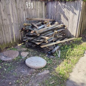 A large pile of wooden planks and yard debris next to a fence for junk removal by Wilsa Junk Removal in Fort Lauderdale, FL.