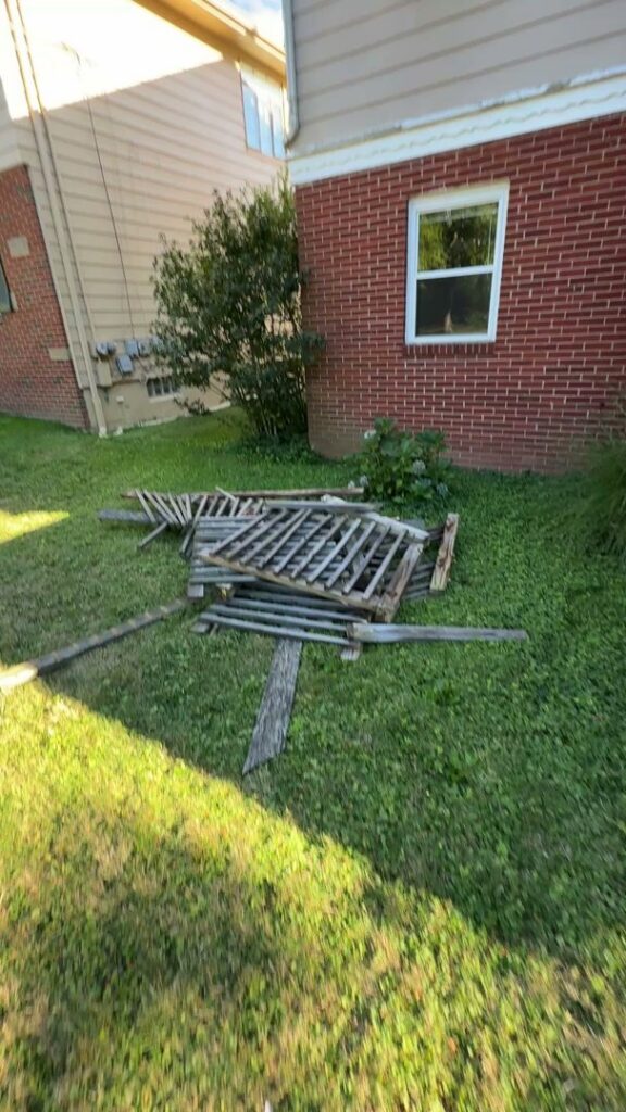 A pile of wooden fence debris on a lawn, awaiting removal by Black Diamond Junk Removal in Bedford Heights, OH.
