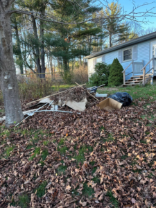 A large pile of mixed yard debris and junk materials on a lawn next to a house, awaiting removal by Averson Hauling & Disposal LLC in Lebanon, ME