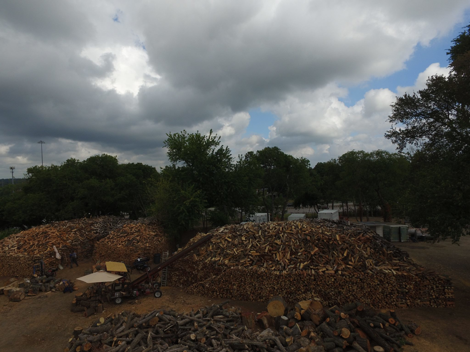 Large piles of firewood and logs with a log splitter at Personal Touch Tree Service in Dallas, TX