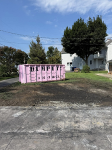 A pink dumpster from Dump It placed in a residential yard for junk removal in Middletown, DE