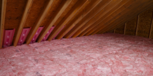Pink fiberglass batt insulation and vent baffles installed in an attic by Attic Insulation of Memphis in Byhalia, MS.