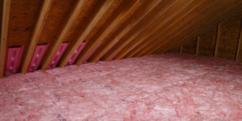 Pink fiberglass batt insulation and vent baffles installed in an attic by Attic Insulation of Memphis in Byhalia, MS.