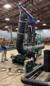 A worker overseeing large pipe fabrication and installation with heavy machinery inside a workshop by Jason Mechanical Corp in Joliet, IL.