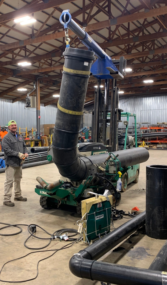 A worker overseeing large pipe fabrication and installation with heavy machinery inside a workshop by Jason Mechanical Corp in Joliet, IL.