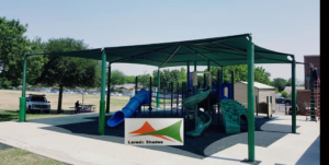 A large green shade structure installed over a playground by Laredo Shades, a general contractor in Laredo, TX.
