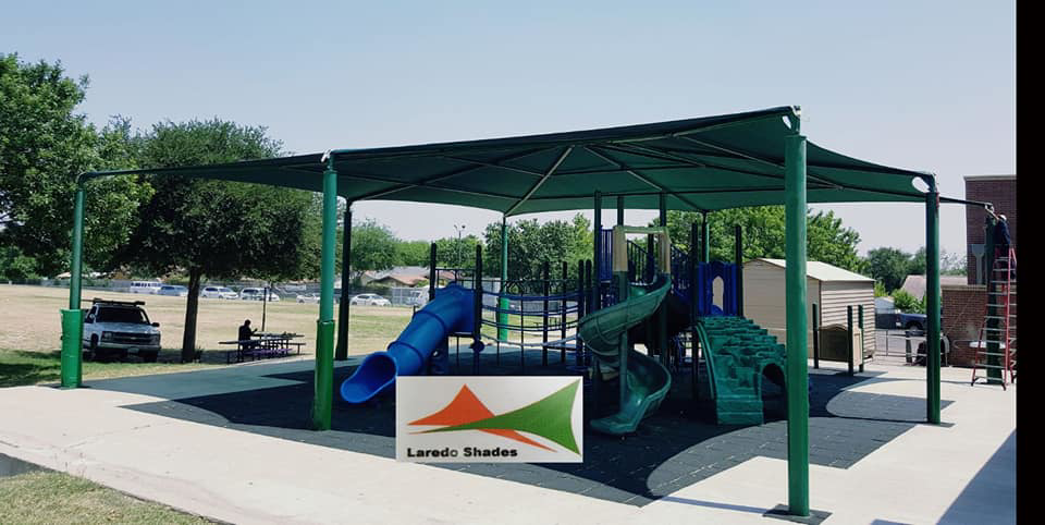 A large green shade structure installed over a playground by Laredo Shades, a general contractor in Laredo, TX.