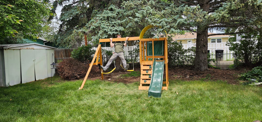 A person testing a newly assembled playset installed by Devil Dog Services LLC in Billings, MT.