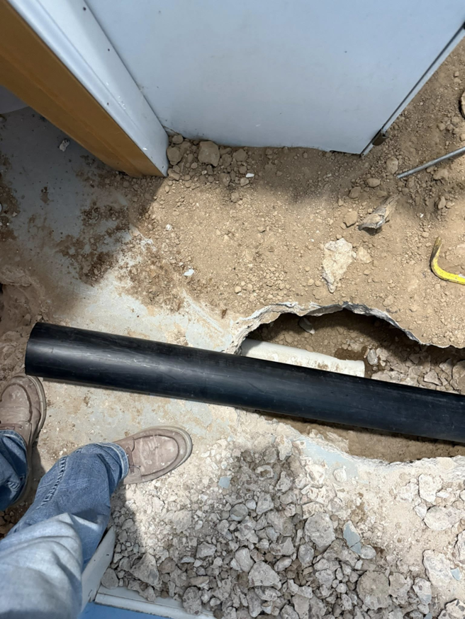 A black drainage pipe being installed in a trench during a plumbing service by AM Remodels LLC in Denver, CO.