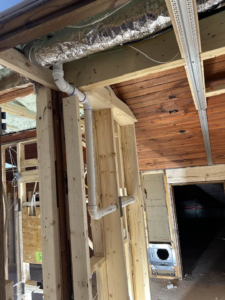 Plumbing pipes and ductwork being installed within wall framing by Haus Builders in Goodhue, MN