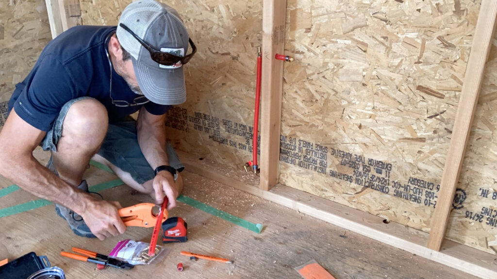 A handyman cutting PEX plumbing pipe during an installation project by Top Shelf Handyman Pros in Post Falls, ID