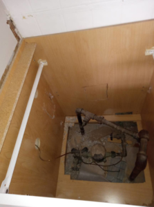Exposed plumbing and utility connections inside a cabinet, showing handyman repair work by Charles and Drew Project Page in Detroit, MI.