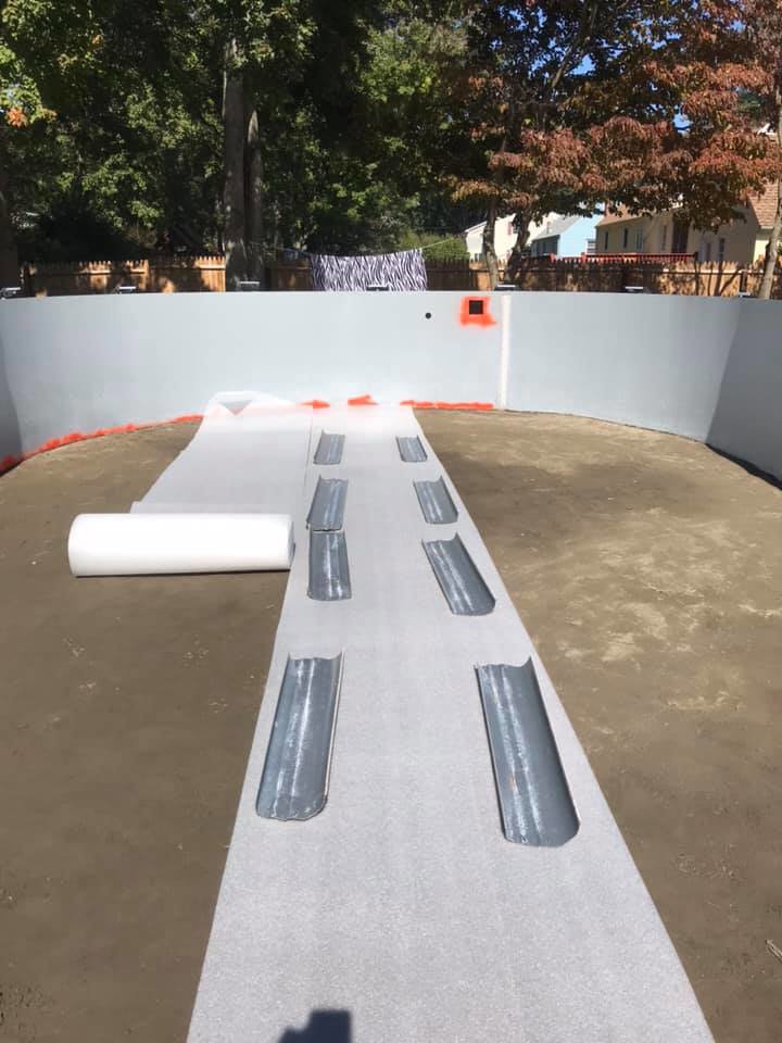 Insulation and padding being laid on the base of an above-ground pool during installation by Advanced Pools and Repair, LLC in Bristol, CT.