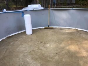 The prepared sand base inside an above-ground pool structure with a broom, ready for liner installation by Advanced Pools and Repair, LLC in Bristol, CT.