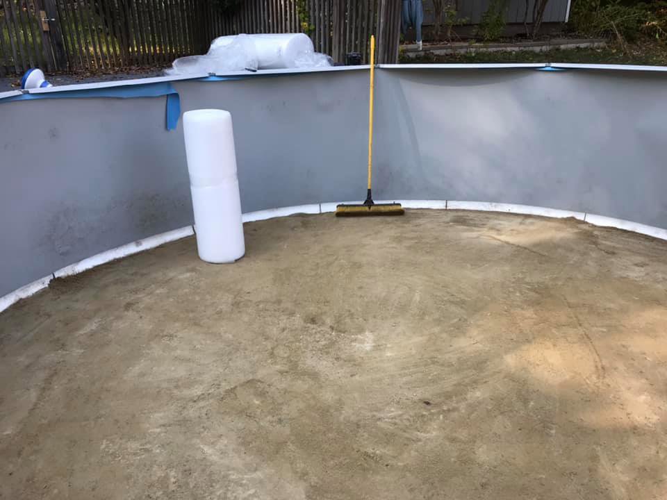 The prepared sand base inside an above-ground pool structure with a broom, ready for liner installation by Advanced Pools and Repair, LLC in Bristol, CT.