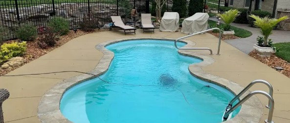 An automatic cleaner maintaining a kidney-shaped pool, showcasing pool cleaning services by Creative Pools and Hardscape in Franklin, TN.