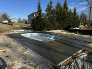 A new pool under construction with freshly poured concrete decking by Sublime Pools RVA in Richmond, VA.
