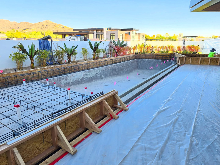 Pool construction in progress with rebar, forms, and a worker from Premier Paradise, Inc. in Gilbert, AZ.