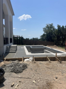 Ongoing pool construction with concrete being poured for the deck by Austin Pool Plastering, a general contractor in Austin, TX.