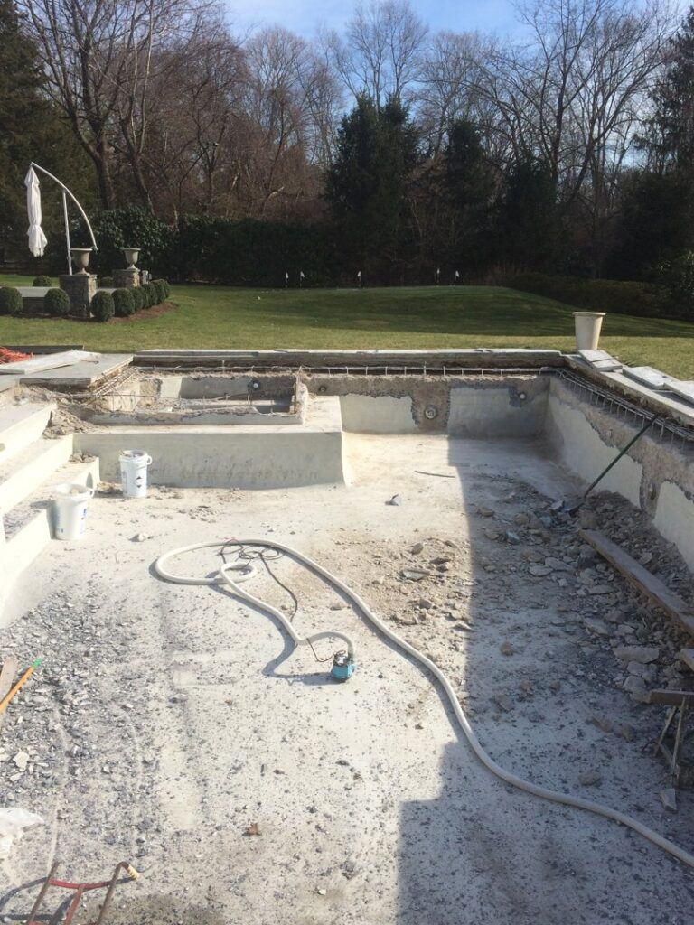 An empty swimming pool undergoing demolition or major renovation, with construction debris and tools, by B-rod Pool Service LLC in Norwalk, CT.