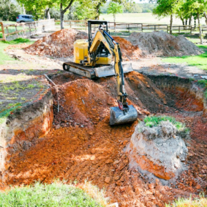 An excavator digging a large hole for new pool construction by Premier Pools & Spas - Charleston in North Charleston, SC