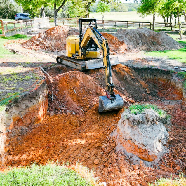 An excavator digging a large hole for new pool construction by Premier Pools & Spas - Charleston in North Charleston, SC